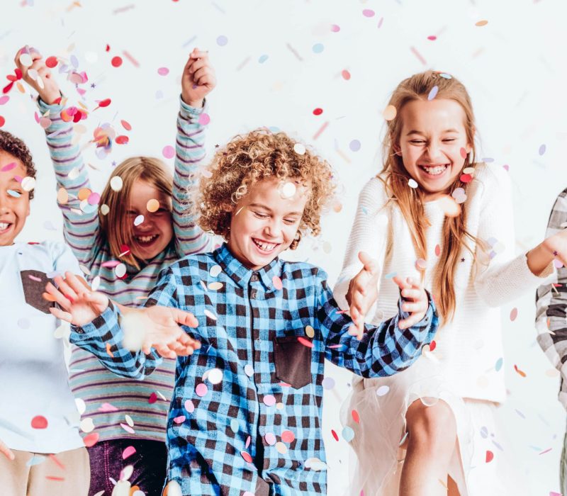 Happy,Kids,Throwing,Colorful,Confetti,In,A,Room